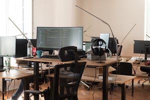 Büroeinrichtung mit Bildschirmen, Stühlen und Tischen